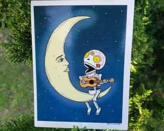 May include: A sugar skull skeleton with a pink and yellow floral design on its head is sitting on a crescent moon and playing a guitar. The moon is against a dark blue starry night sky.