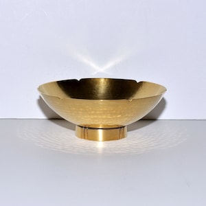 Puede incluir: Un cuenco de metal dorado martillado con un borde festoneado y una base corta y cil&iacute;ndrica.