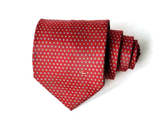 May include: A red silk tie with a small, repeating pattern of blue, white, and yellow circles. The tie is folded and tied in a knot.