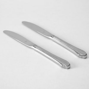 May include: Two silver dinner knives with ornate handles.
