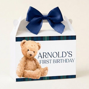 Può includere: Scatola regalo bianca con fiocco blu navy. La scatola presenta un'illustrazione di orsetto e la scritta "ARNOLD'S FIRST BIRTHDAY". Un motivo a quadri blu, verdi e rossi borda la scatola.