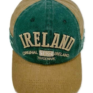 May include: A green and brown baseball cap with the word "IRELAND" embroidered in white on the front. The cap also has the words "ORIGINAL", "TRADE MARK", and "IRELAND" embroidered on the front.