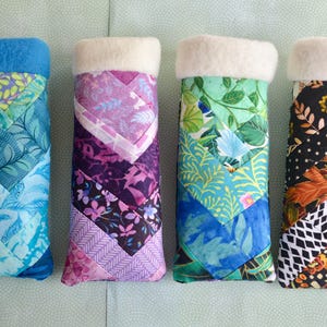May include: Four fabric covered eyeglass cases with a white fleece lining. The cases are made of patchwork fabric with different patterns and colors, including blue, green, purple, and black.