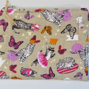 May include: A beige zippered pouch with a quilted texture. The pouch features a repeating pattern of cats, butterflies, and flowers in shades of pink, grey, and white.