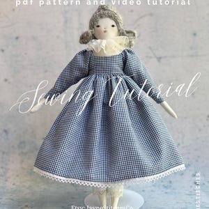 May include: A fabric doll with grey yarn hair, wearing a blue and white gingham dress with long sleeves, a white lace collar, and white lace-trimmed bloomers. Text reads: THE BLUEBELL DRESS pdf pattern and video tutorial Sewing Tutorial.