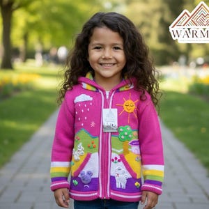 May include: A pink hooded zip-up sweater with colorful embroidered designs of a sun, clouds, and animals. The sweater has rainbow stripes on the cuffs and hood trim. The brand logo "WARMIUK" is visible in the top right corner.