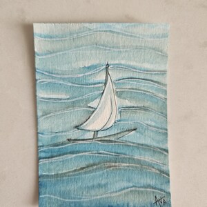 May include: Watercolor painting of a sailboat on blue water. The boat has a white sail and a black hull. The water is depicted with wavy blue brushstrokes. The artist's signature, "AVA", is in the bottom right corner.