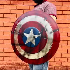 May include: A red, white, and blue Captain America shield with a distressed, weathered look. The shield has a large white star in the center.