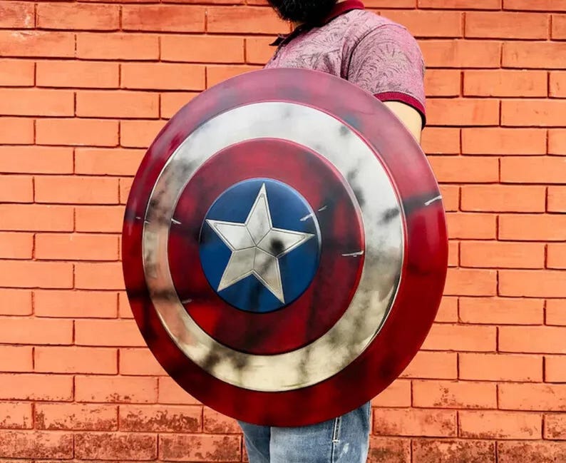 May include: A red, white, and blue Captain America shield with a distressed, weathered look. The shield has a large white star in the center.