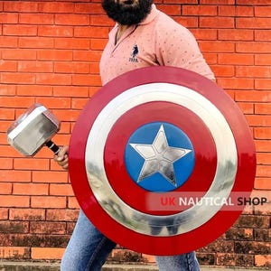 May include: A person holding a silver and black Thor's hammer and a red, white, and blue Captain America shield. The shield has a large silver star in the center. The text "UK NAUTICAL SHOP LTD" is visible on the shield.
