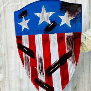 May include: A red, white, and blue shield with black paint splatters and the text "Iron Clad Armory".