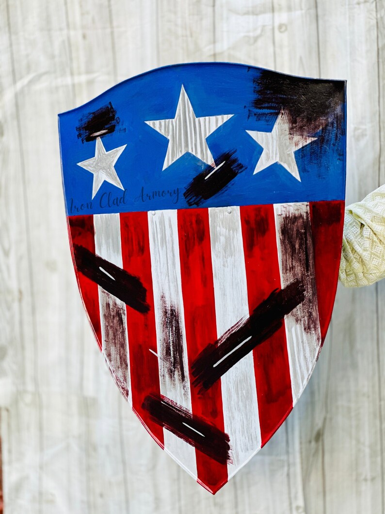 May include: A red, white, and blue shield with black paint splatters and the text "Iron Clad Armory".