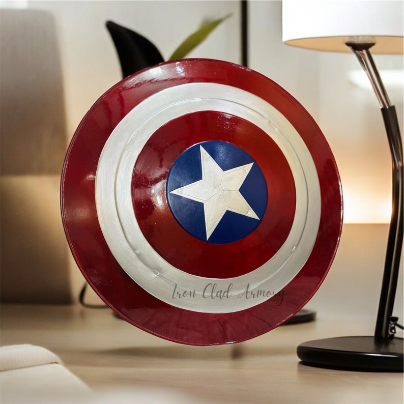 Pu&ograve; includere: Uno scudo di Capitan America rosso, bianco e blu con una stella a cinque punte al centro. Lo scudo ha un bordo argentato e le parole "Iron Clad Armory" sono stampate in basso.