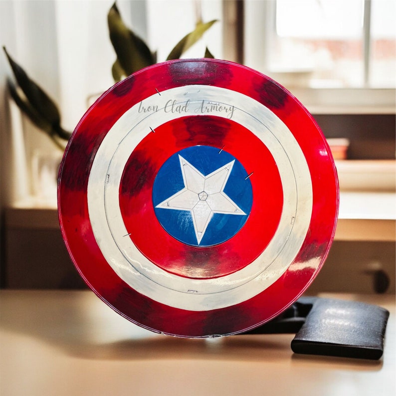 Pu&ograve; includere: Uno scudo di Capitan America rosso, bianco e blu con il testo "Iron Clad Armory" in alto. Lo scudo &egrave; fatto di un materiale plastico duro e ha una stella in rilievo al centro.