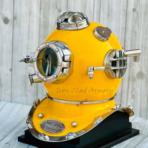 Peut inclure: Un casque de plongée jaune avec des accents argentés et une base noire. Le casque a une grande fenêtre ronde, une petite fenêtre ronde et une bouche d'aération rectangulaire. Le casque est marqué "Iron Clad Armory" et "U.S. Navy Mark V Diving Helmet".