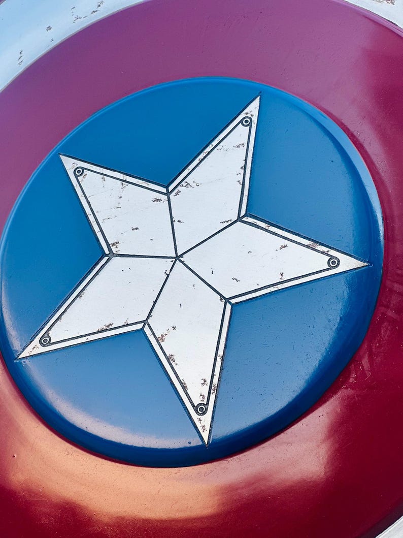 K&ouml;nnte beinhalten: Nahaufnahme eines rot-wei&szlig;-blauen Schildes mit einem wei&szlig;en f&uuml;nfzackigen Stern in der Mitte. Der Stern hat einen abgenutzten, alten Look und ist von einem blauen Kreis umgeben.