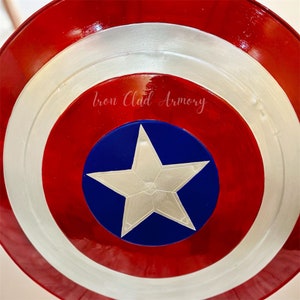 Pu&ograve; includere: Uno scudo di Capitan America rosso, bianco e blu con una stella bianca al centro. Lo scudo ha il testo "Iron Clad Armory".
