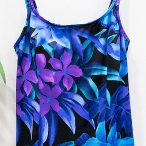 Puede incluir: Un ba&ntilde;ador negro con estampado tropical con flores y hojas azules, moradas y turquesa.