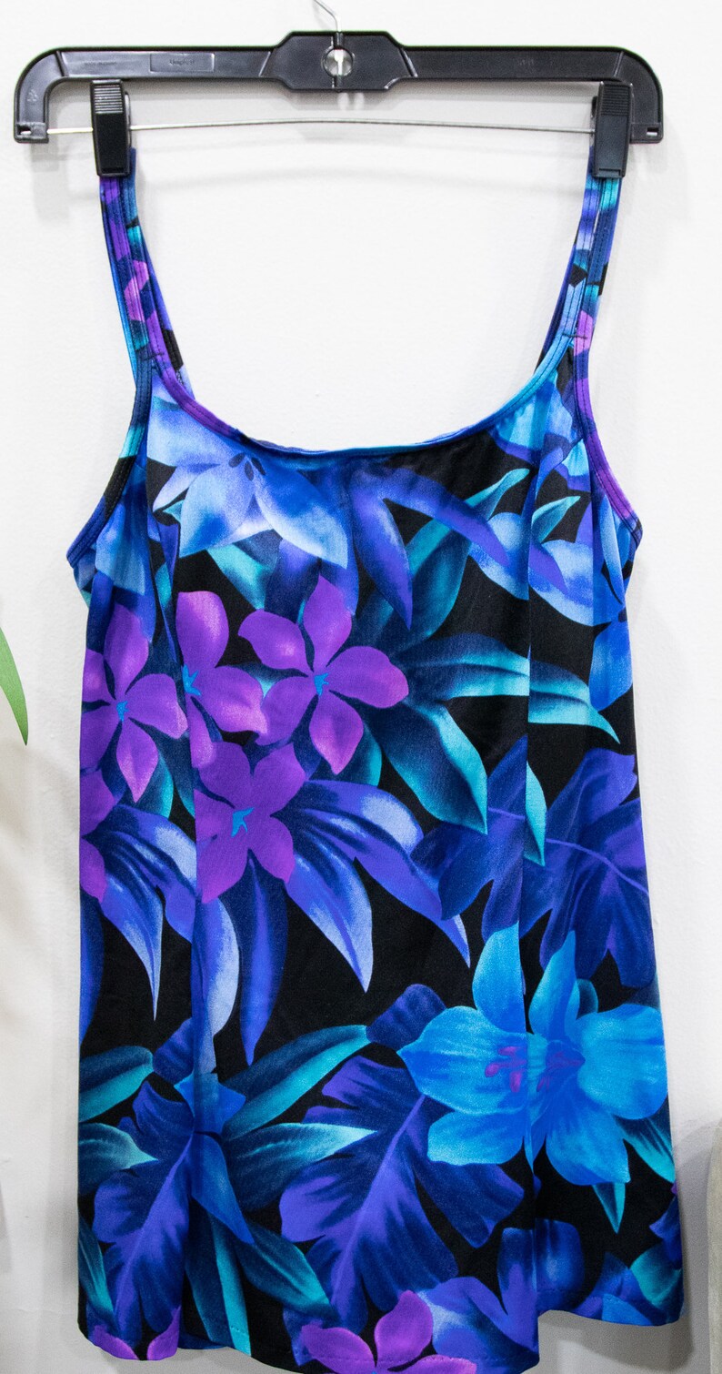 Puede incluir: Un ba&ntilde;ador negro con estampado tropical con flores y hojas azules, moradas y turquesa.