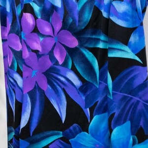 Puede incluir: Un ba&ntilde;ador negro con estampado tropical con flores y hojas azules, moradas y turquesa.