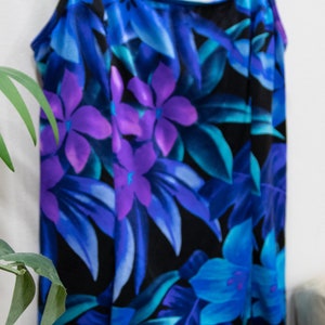 Puede incluir: Un ba&ntilde;ador negro con estampado floral con flores y hojas azules, moradas y turquesa.