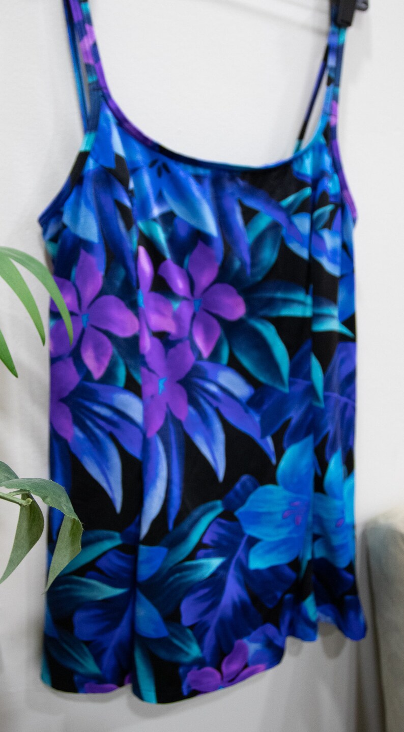 Puede incluir: Un ba&ntilde;ador negro con estampado floral con flores y hojas azules, moradas y turquesa.