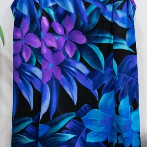 Puede incluir: Un ba&ntilde;ador negro con estampado tropical con flores y hojas azules, moradas y verde azulado.