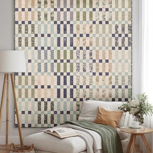 May include: A square quilt featuring a grid pattern of rectangular fabric blocks in shades of sage green, navy blue, cream, and light blue. The design incorporates various floral and geometric prints, with small dark navy squares at the intersections.