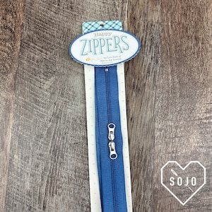 May include: A blue zipper with a silver pull and a white card with the text "Happy Zippers by Lori Holt of Bee in my Bonnet".