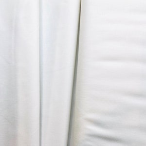 May include: Two pieces of white fabric, one folded over the other, showing the texture of the fabric.