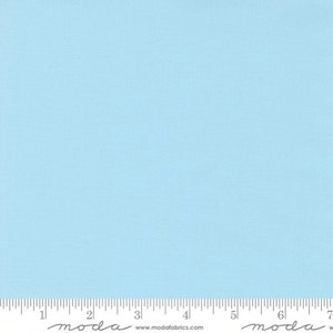May include: A solid light blue fabric with a textured appearance. The fabric is marked with a ruler along the bottom edge, with the word "moda" printed at the bottom. The fabric is suitable for quilting and sewing projects.