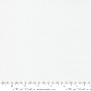 May include: A plain white fabric with a subtle texture. The fabric is measured with a ruler that has the word "moda" printed on it.