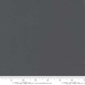 May include: A solid charcoal gray fabric swatch with a ruler showing 7 inches. The ruler has the word "moda" printed on it.