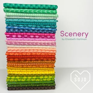May include: A tall stack of folded fabric squares featuring a diverse range of colors including green, blue, pink, orange, yellow, and brown. Each piece of fabric displays a unique geometric or floral pattern. The text Scenery by Elizabeth Hartman is visible.