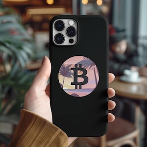 May include: Black phone case with a round sticker featuring a stylized Bitcoin symbol on a pink and orange sunset beach scene with palm trees.