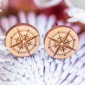 May include: Two wooden compass earrings with a brown wood finish and a laser-etched compass design.