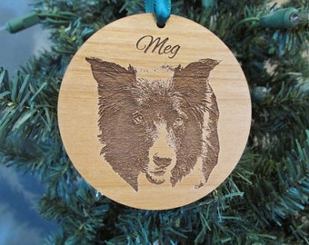 May include: A wooden Christmas ornament with a black and white dog's face engraved on it. The ornament is round and has the name "Meg" engraved on it.
