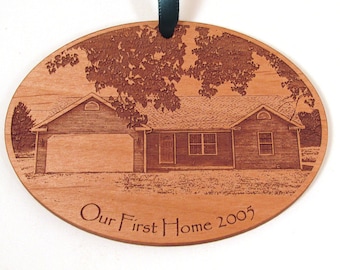 May include: A wooden oval ornament with a laser-engraved image of a house and trees. The text "Our First Home 2005" is engraved below the image.