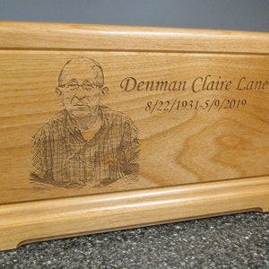 May include: A wooden box with a photo and inscription. The inscription reads "Denman Claire Lane 8/22/1931-5/9/2019".