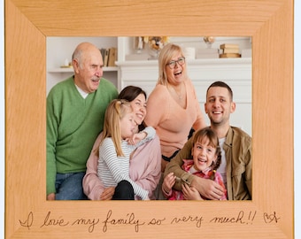 May include: A light-colored wooden picture frame with a family portrait. The frame has the inscription "I love my family so very much!!" in a handwritten style. The family includes two young girls, two adults, and two older adults.