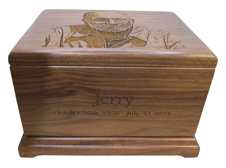 May include: A wooden cremation urn with a personalized inscription. The urn features a laser-engraved portrait of a man with the name "Jerry" and the dates "October 26th, 1958 - July 30, 2021".