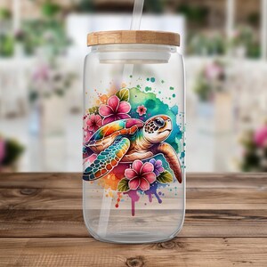 Pode incluir: Uma garrafa de &aacute;gua de vidro transparente com tampa de bambu e um design de aquarela colorido de uma tartaruga marinha nadando atrav&eacute;s de flores. A garrafa tem um canudo.