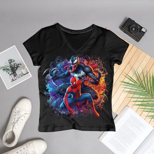 May include: Black t-shirt with a colorful graphic print of Spider-Man and Venom. The graphic features a blue and purple background with orange and yellow accents.