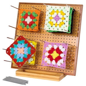 May include: A bamboo crochet project display stand with four colourful crochet squares, each with a different pattern, displayed on the stand. The stand has a pegboard design and comes with 12 metal pins.
