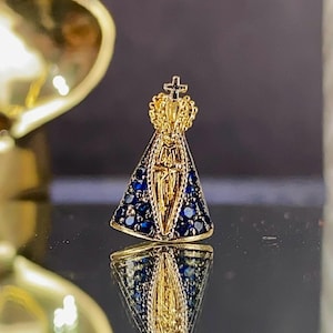 May include: Gold-toned pendant featuring a depiction of the Virgin Mary with a blue crown and blue gemstone accents.