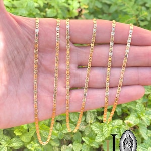 May include: Five gold chains with a delicate, patterned design. The chains are arranged in a row, with the longest chain at the top and the shortest chain at the bottom.