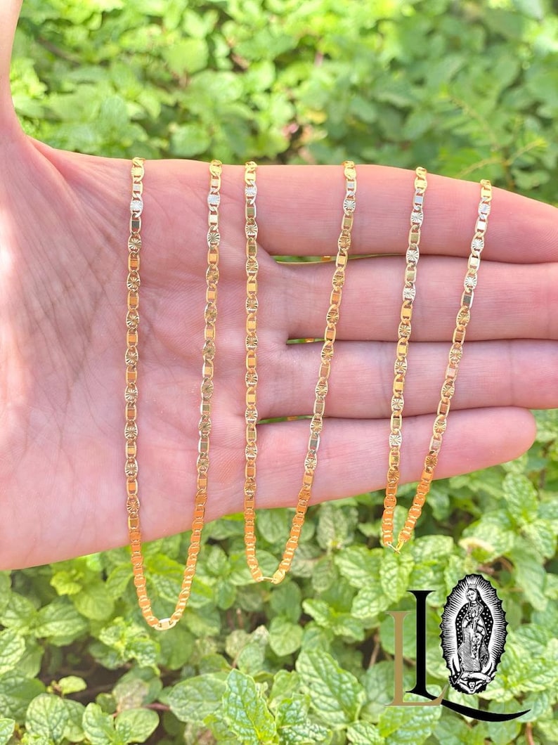 May include: Five gold chains with a delicate, patterned design. The chains are arranged in a row, with the longest chain at the top and the shortest chain at the bottom.