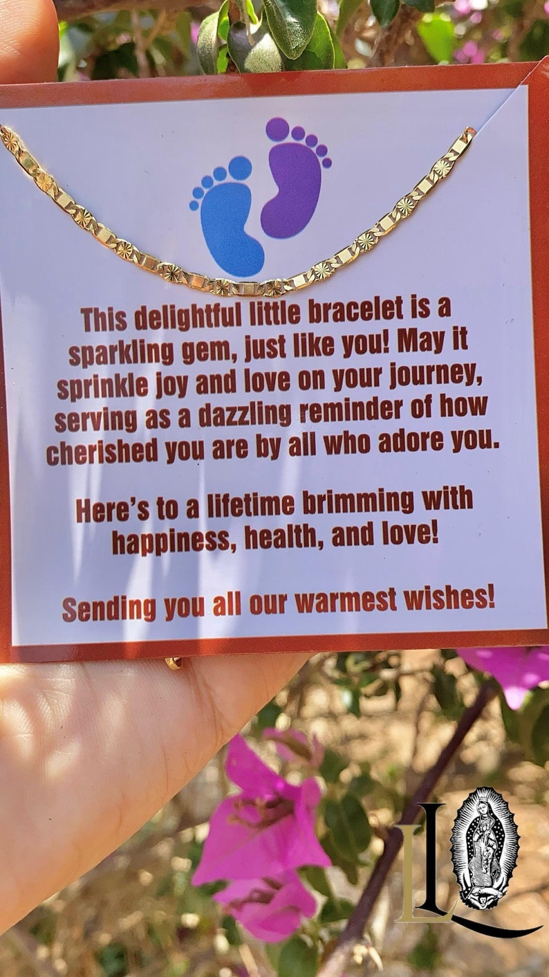 May include: A gold bracelet with a delicate design, presented on a card with a message about joy, love, and happiness. The card features a blue and purple footprint design.