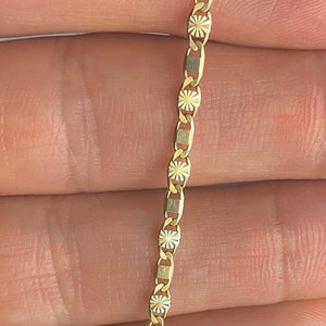 May include: A gold chain necklace with a delicate, patterned design. The chain is made of small, linked pieces that are intricately detailed.