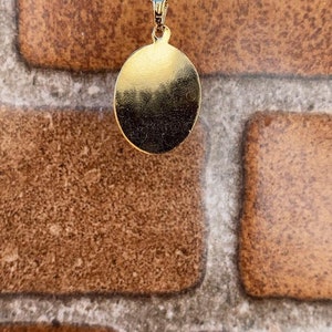 May include: A gold chain necklace with a round pendant. The pendant is smooth and has a shiny finish.